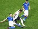 MEZI DVMA. Mesut Özil, nmecký pílmachr, se dostal do obleení dvou italských...