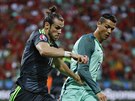 Velan Gareth Bale zkouí uniknout portugalskému kapitánovi Cristianu Ronaldovi.
