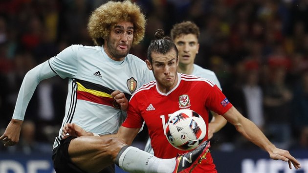 Belgický záložník Marouane Fellaini odkopává balon Garethu Baleovi.