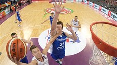 Lotyšský basketbalista Dairis Bertans donáší míč do českého koše, o blok se...
