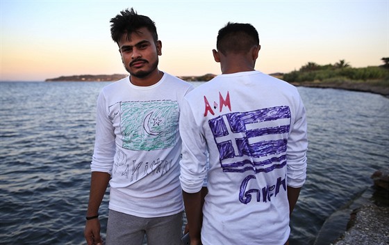 Migranti z Pákistánu na ostrov Lesbos ukazují trika, na kterých mají...