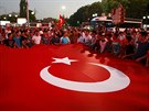 Píznivci tureckého prezidenta drí obrovskou státní vlajku ped budouvou...