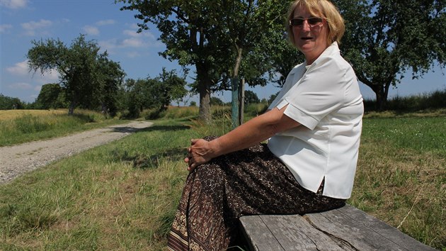 Marie Šimůnková sedí na Cimrmanově lavičce nedaleko Vesce u Sobotky. V pozadí je polní cesta, po které v komedii Jára Cimrman ležící, spící, hlavní hrdina opouštěl vesnici.