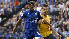 Záloník Leicesteru Rijád Mahriz hlídá balon ped Laurentem Koscielnym,...