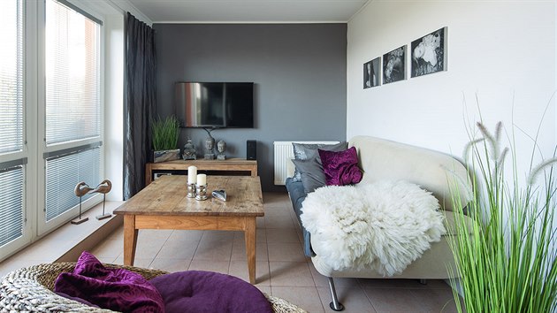 Obývací pokoj je spojený s terasou a zahradou, a tak si rodina pochvaluje dlažbu na podlaze. Nábytek je přestěhovaný z bývalého domu. Modernější atmosféru udělala šedá výmalba, závěsy či černobílé fotografie.