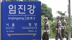 Jihokorejtí vojáci procházejí kolem cedule, oznaující vzdálenost Soulu a...