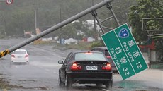A car runs past a collapsed traffic sign, toppled by strong winds of typhoon...