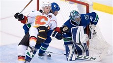 Matt Stajan z Calgary zlobí ped brankou Vancouveru. Brání ho Philip Larsen, ve...