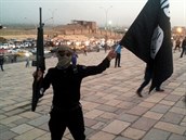 Bojovník Islámského státu v Iráku a Levantě (ISIL) drží zbraň a vlajku ISIL na...