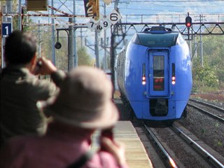 Cestující si fotí příjezd expresu Super Ozora do stanice Šintoku na trati z...