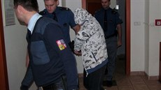 V�ze�ská eskorta vede ob�alovaného, který se sna�í skrýt p�ed objektivem.