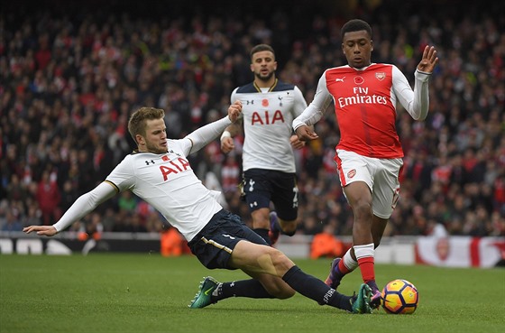 Eric Dier v dresu Tottenhamu zastavuje Alexe Iwobiho z Arsenalu.