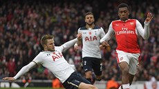 Eric Dier v dresu Tottenhamu zastavuje Alexe Iwobiho z Arsenalu.
