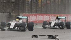Lewis Hamilton a Nico Rosberg se vyhýbají troskám z auta Kimiho Räikkönena,...