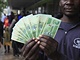 Mu pzuje s novmi bankovkami ped bankou v Harare (28. listopadu 2016)