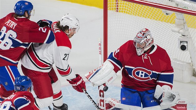 Justin Faulk z Caroliny v anci ped montrealskm brankem Careym Pricem.  Brn ho Jeff Petry.