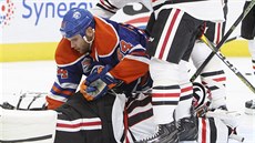 Zack Kassian z Edmontonu po sráce s brankáem Chicaga Coreym Crawfordem.