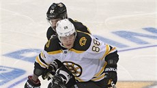 David Pastrák (v bílém) z Bostonu jde za pukem, pronásleduje ho Sidney Crosby...