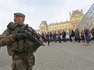 Francouzský voják na silvestra u Louveru, turisté za ním �ekají frontu na vstup...