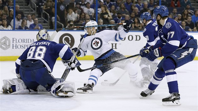 Ondej Palt z Tampy zskv kotou, Joel Armia z Winnipegu ped brankou soupee pad.