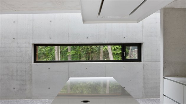 Pohledový beton je dominantním prvkem interiérového designu. Vidět je zčásti otvíravé pásové okno.