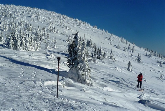 Turisté stoupají vzhůru po upravené lyžařské magistrále. Zapadané obtížně schůdné cesty k hřebenům hor je nelákají. 