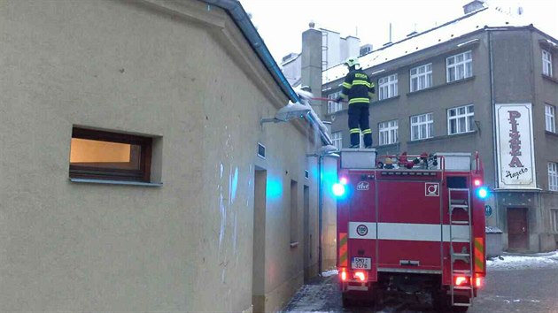 Hasiči odklízejí z budovy veřejných toalet v Prostějově sníh a led ohrožující vcházející či vycházející lidi.