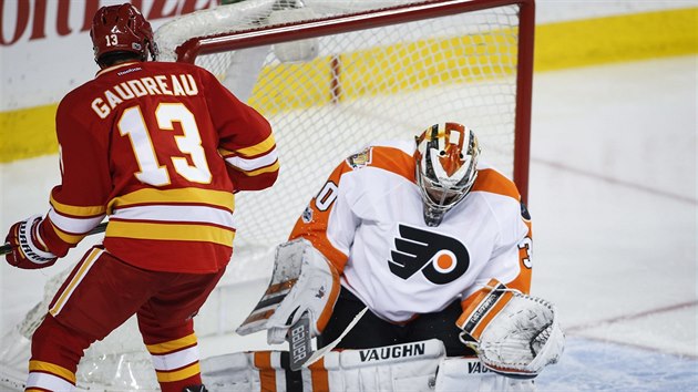 Michal Neuvirth v brance Philadelphie zasahuje proti stele Johnnyho Gaudreaua z Calgary.