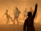 FOTBAL V INDII. Chlapci obklopení prachem soupeí o mí bhem fotbalového...