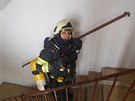 Dobrovolní hasii z Prahy 11 vynáejí po schodech dýchací pístroje.