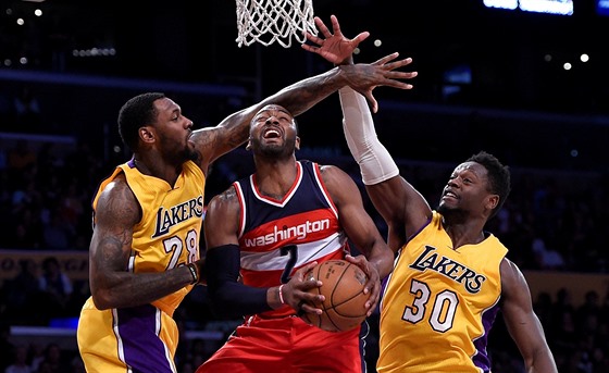 John Wall z Washingtonu úpí mezi Tarikem Blackem (vlevo) Juliusem Randlem z Los...