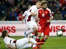 Lotyský obránce Kaspars Gorks skluzem brzdí prnik výcarského fotbalisty...