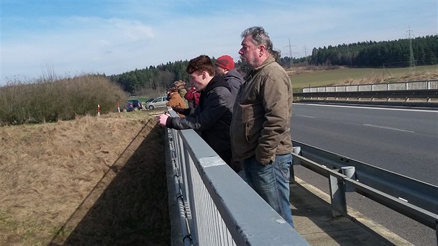 Lidé čekají na mostě přes dálnici na příjezd amerického vojenského konvoje (25. března 2017).