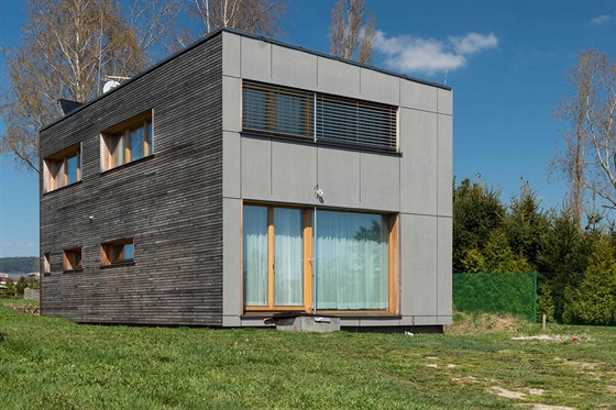 Fasáda domu je z neošetřeného modřínového dřeva a šedivých vláknocementových...