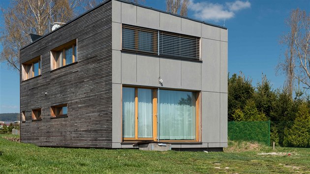 Fasáda domu je z neošetřeného modřínového dřeva a šedivých vláknocementových desek. 