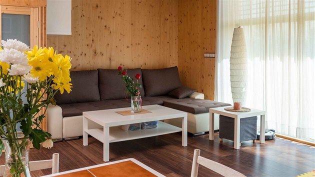 Všudypřítomné dřevěné povrchy masivních panelů i trámový strop utvářejí útulnou domácí atmosféru. Obývací pokoj ještě získá na atraktivnosti s vybudováním navazující terasy.