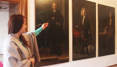 Prvodkyn z mantínského zámku Mirka Topinková ukazuje portréty sluebnictva...