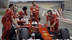 Mechanici z Ferrari odtlačují porouchaný vůz Sebastiana Vettela.
