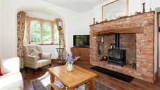 V obývací části je velké okno a dekorativní viktoriánská litinová kamna ve...