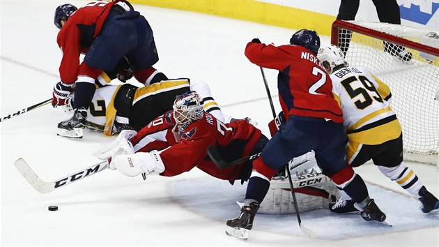 Brank Braden Holtby z Washingtonu se vrh po puku v utkn proti Pittsburghu. Vpravo se petlauje dvojice Matt Niskanen (2) a Jake Guentzel.