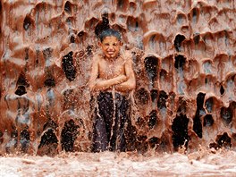 PINAVÉ OSV̎ENÍ. Afghánský chlapec se ochlazuje pod bahnitým vodopádem na...
