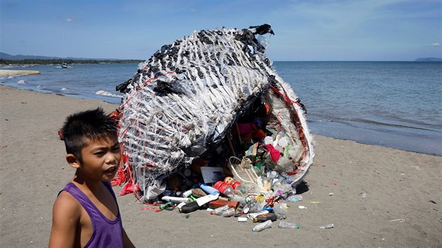 PLASTOVÁ VELRYBA. Chlapec stojí vedle umělecké plastiky ve tvaru velryby, která leží na pobřeží u obce Naic na Filipínách. Z odpadků a plastů ji vyrobila organizace pro ochranu životního prostředí Greenpeace. 