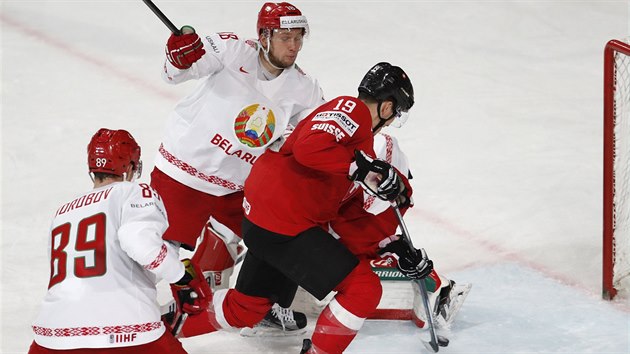 Švýcarský hokejista Reto Schappi (v červenočerném) posílá puk do běloruské sítě.