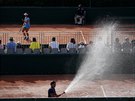 Poadatelé kropí dvorce bhem devátého hracího dne Roland Garros.