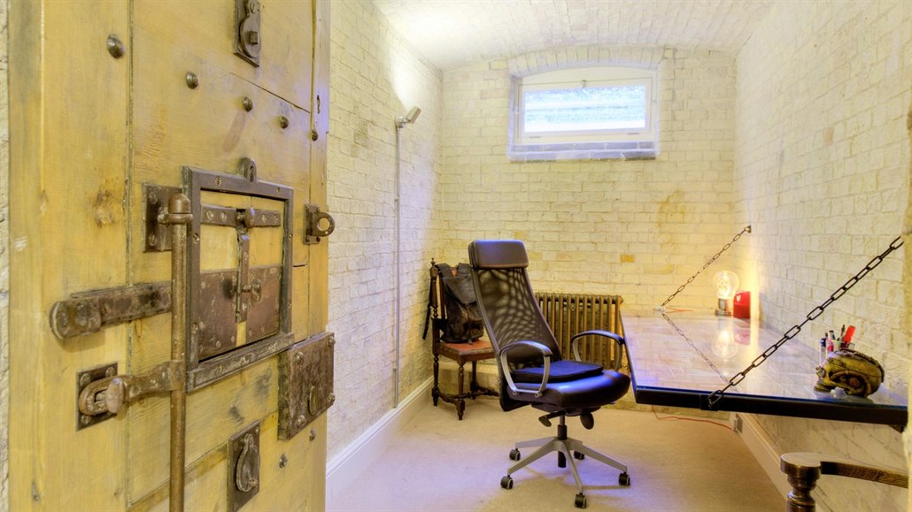 V jedné původní cele je pracovna se stolem v podobě vězeňského lůžka. 