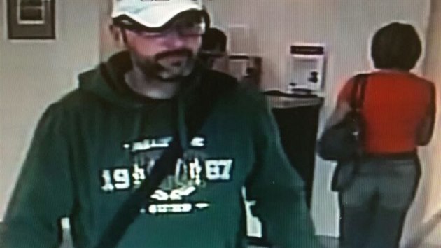 Vousatý muž v kšiltovce, který loupil v kadaňské bance, na snímku z bezpečnostní kamery.