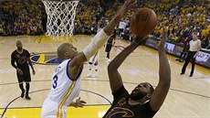 David West (v bílém) z Golden State pi snaze zablokovat Tristana Thompsona z...