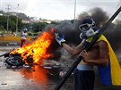 An opposition supporter stands next to a burning riot security force motorcycle...