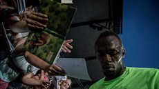 Usain Bolt se podepisuje fanoukm na Zlaté trete.