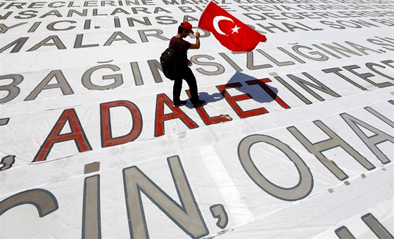 Neznámý mu pechází po nápisu spravedlnost. S sebou nese tureckou vlajku.